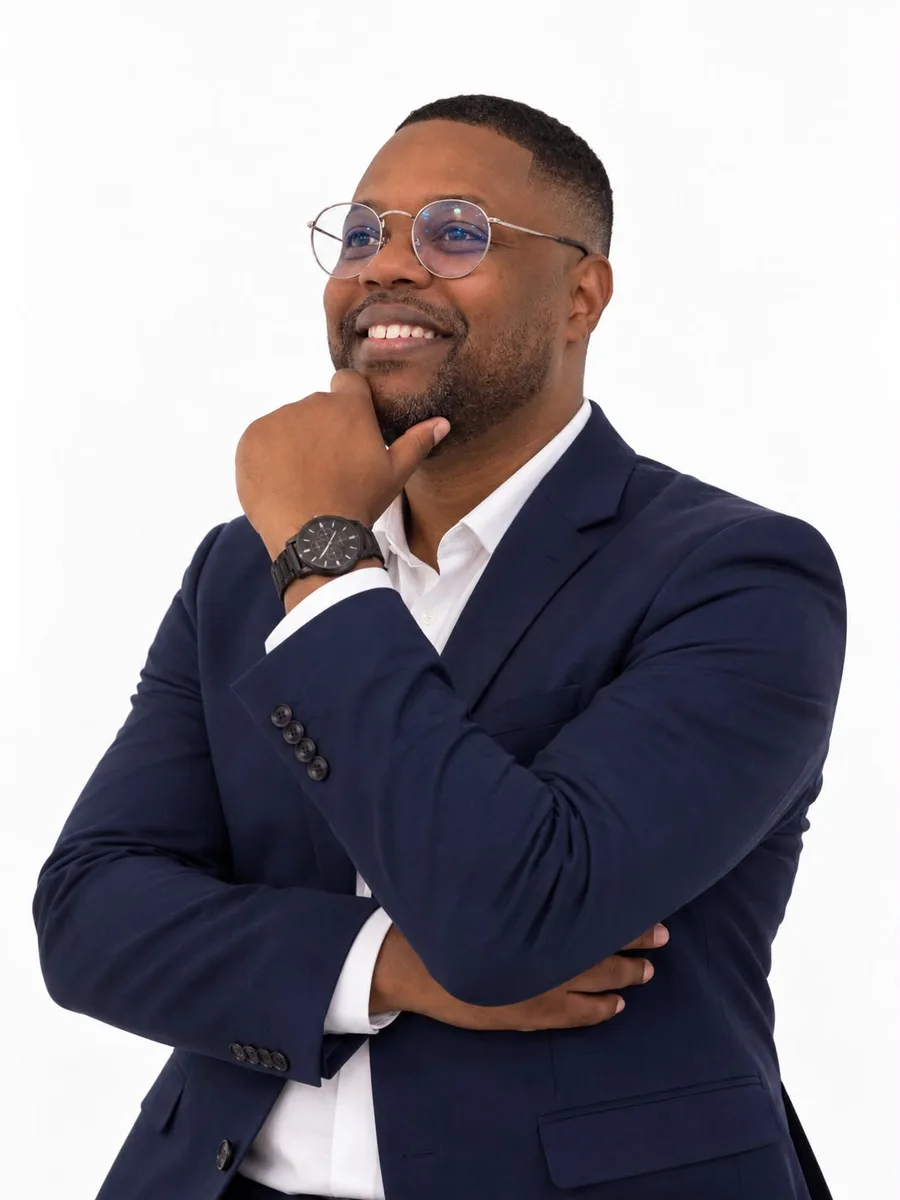 Yossef Leandro, de blazer azul-marinho e camisa branca, sorrindo com a mão apoiada no queixo